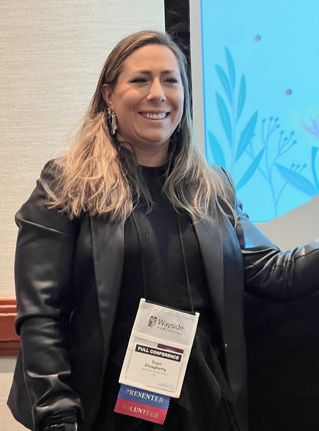 Traci Dougherty smiling at a professional conference while wearing presenter and volunteer credentials